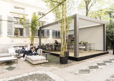 Pergola bioclimatique en aluminium verandair installée dans la cour extérieure d'une bâtisse blanche