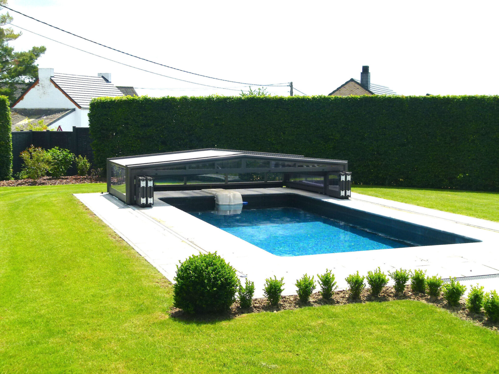 Abri de piscine bas amovible dans un jardin vert et bien entretenu