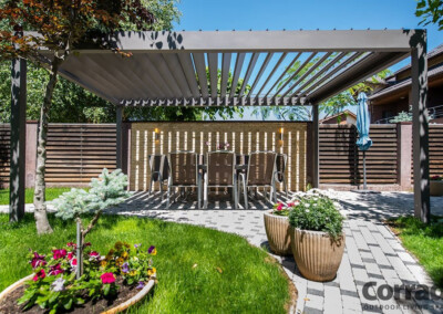 pergola bioclimatique anthracite dans un jardin très fleuri et arboré