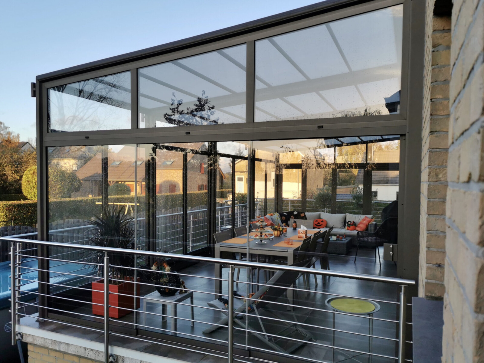 Pergola bioclimatique entièrement vitrée, salle à manger décorée en orange et brun