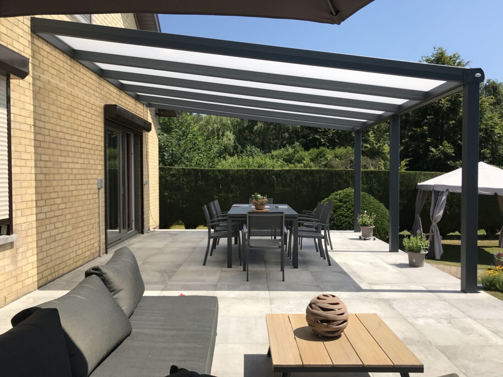 Grande pergola au-dessus d'une terrasse donnant sur un jardin