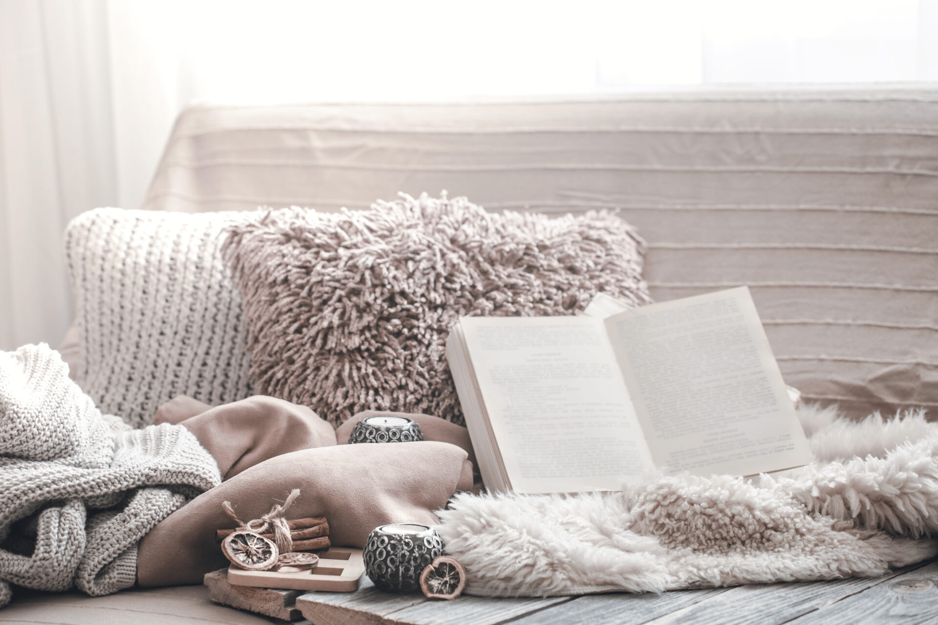 déco chaleureuse dans une véranda: canapé, coussin, livre ouvert