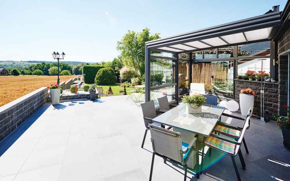 Véranda rétractable sur une terrasse carrelée avec vue sur les champs