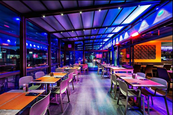 veranda retractable de restaurant avec lumières bleues et roses Verandair