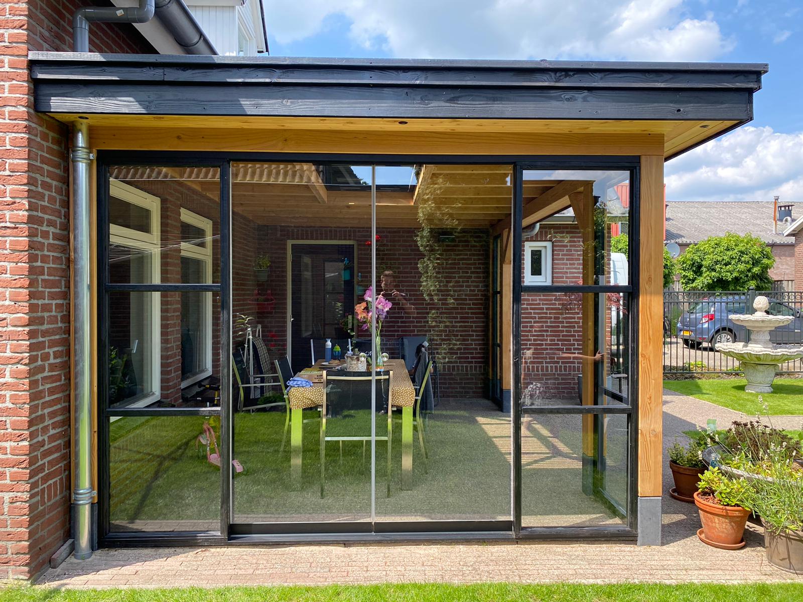 Pergola en bois qui est adossée au mur du maison en briques rouges