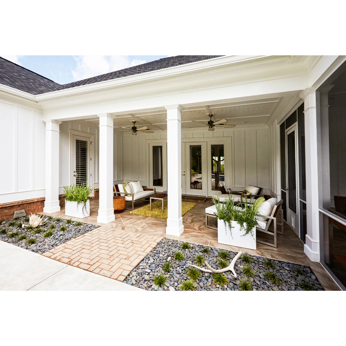 Grand patio blanc avec des poutres qui abrite un salon extérieur cosy