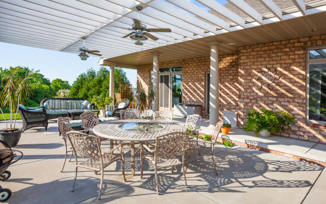 Pergola blanche recouvre une grande terrasse aménagée avec un salon extérieur en tissu et une table avec des chaises