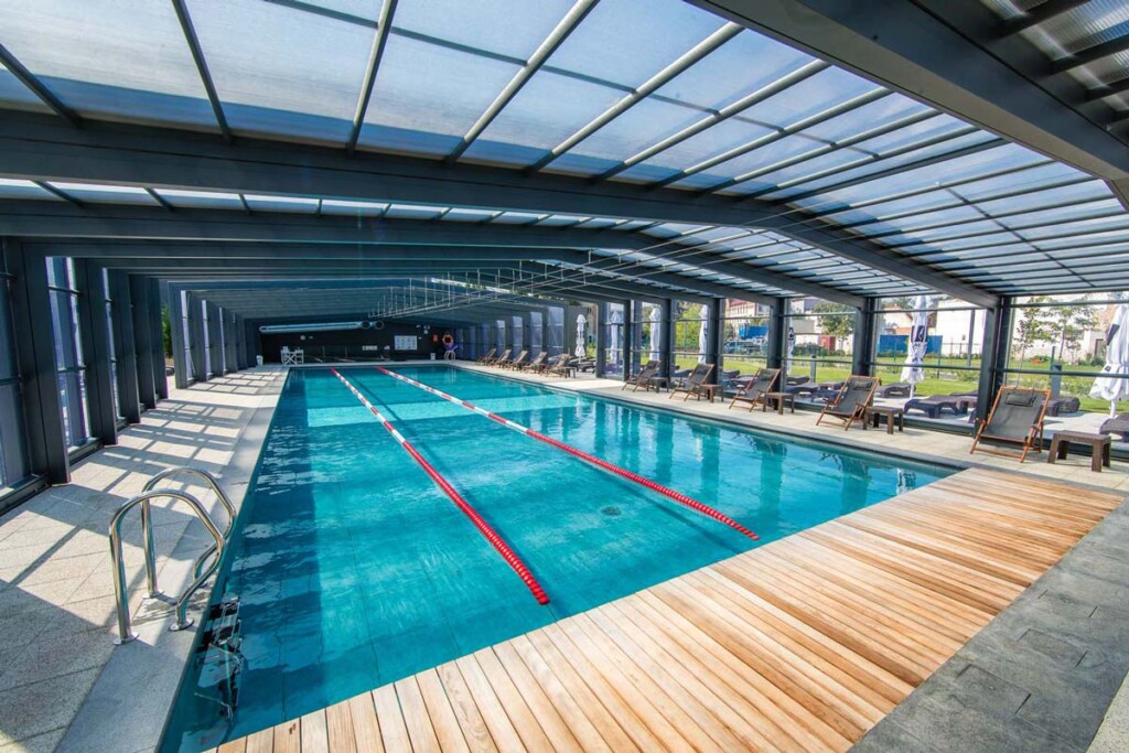 Abri de piscine haut pour collectivité. Il y a une piscine qui est équipée de lignes de flotteurs