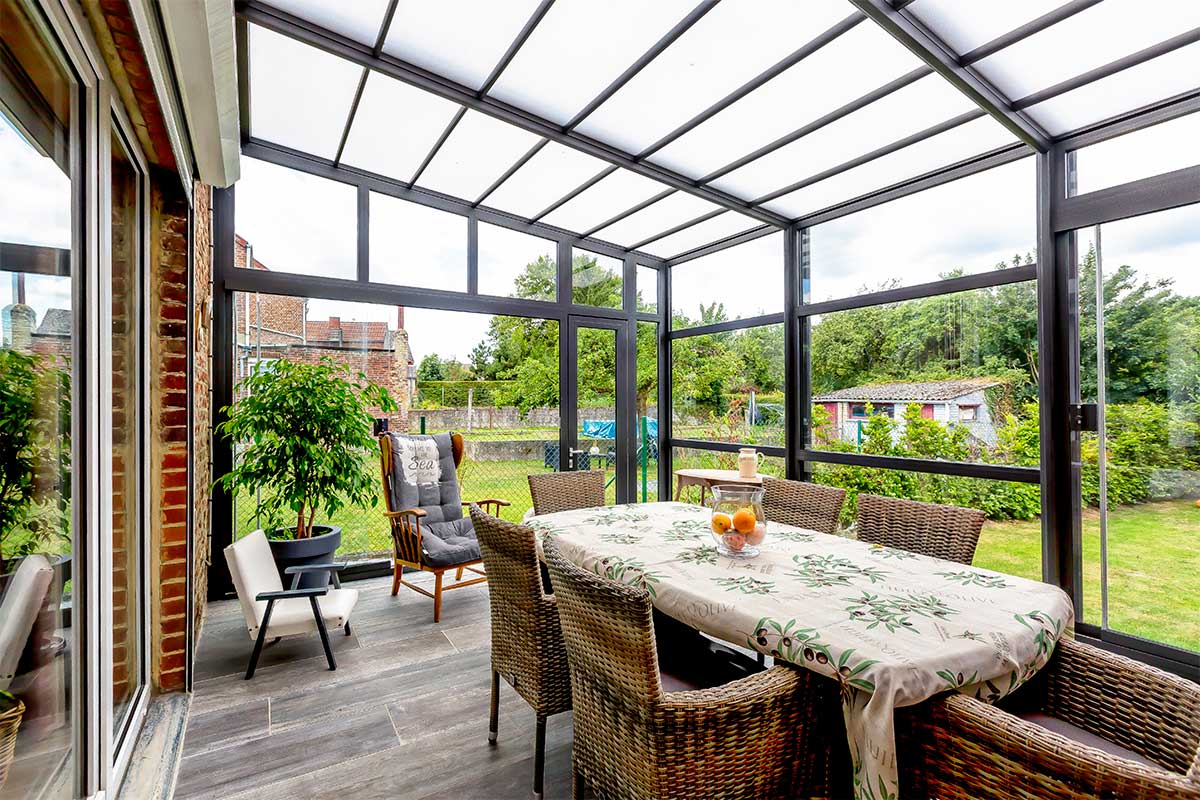 Abri de terrasse rétractable. Il y a une table avec une nappe, des chaises et une vue sur le jardin