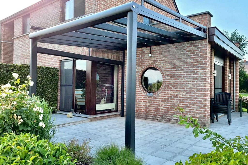 Pergola vitrée ouverte accolée à une maison avec une fenêtre ronde