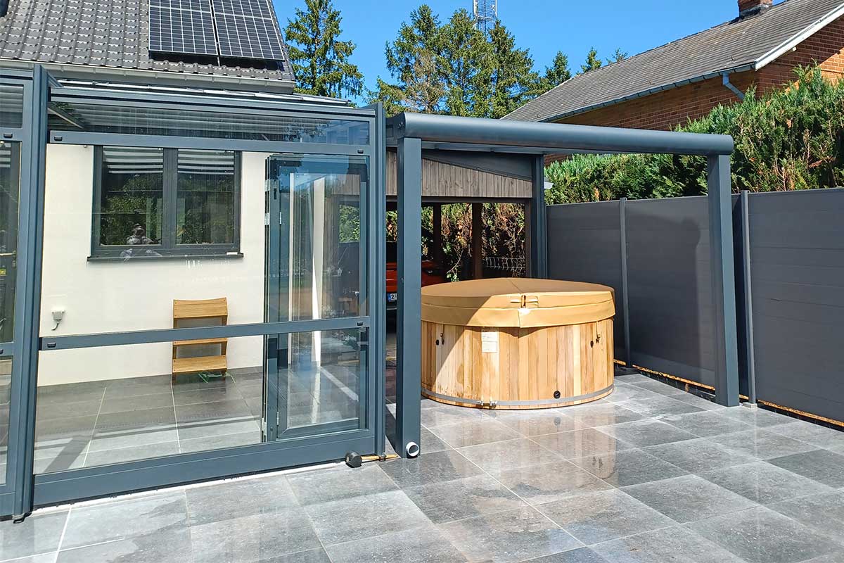 Open spa enclosure and glazed pergola on a terrace with grey tiles and jacuzzi