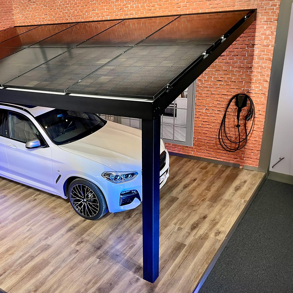 Carport aluminium solaire avec panneaux photovoltaïques sur le toit qui protège une voiture blanche électrique dans un showroom Verandair