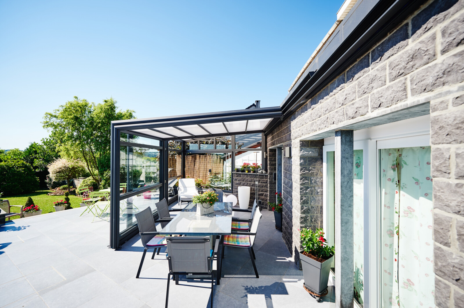 Abri de terrasse rétractable adossé à une maison en briques claires