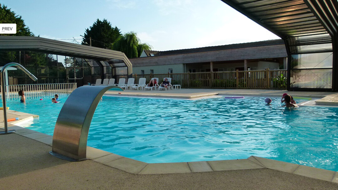 Piscine communale avec un abri de piscine haut où on voit des personnes qui nagent