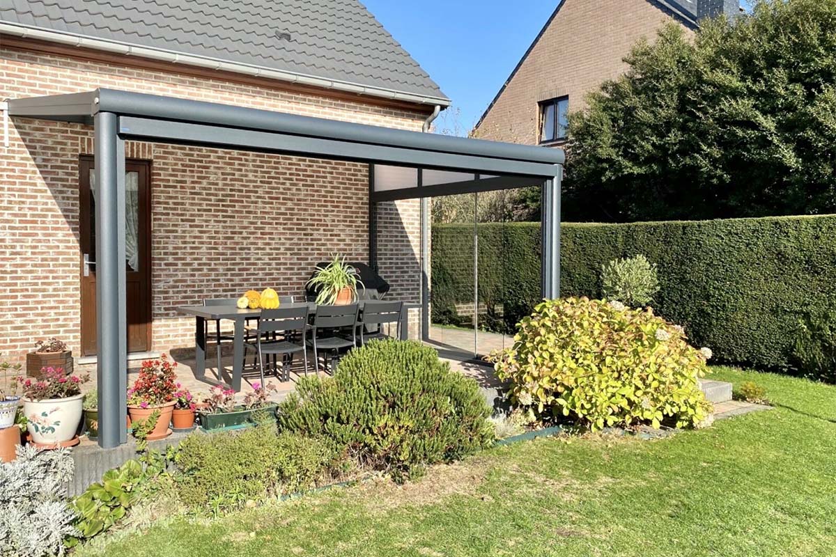 Porte coulissante qui referme un côté d'une véranda. Beau jardin avec des plantes, des fleurs et des légumes