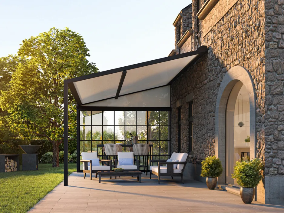 Véranda rétractable sur une terrasse carrelée à ras du jardin, composée d'une table en verre et des chaises en osier